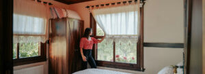 Woman enjoying sunlight in a cozy budget guesthouse room, a perfect example of cheap stays in USA for travelers.